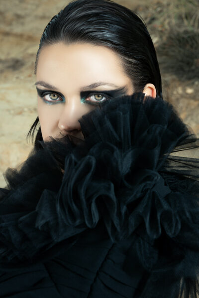 close up of a female model staring intensely into the lens, concentrating on the shapes of the clothing and the dark make up